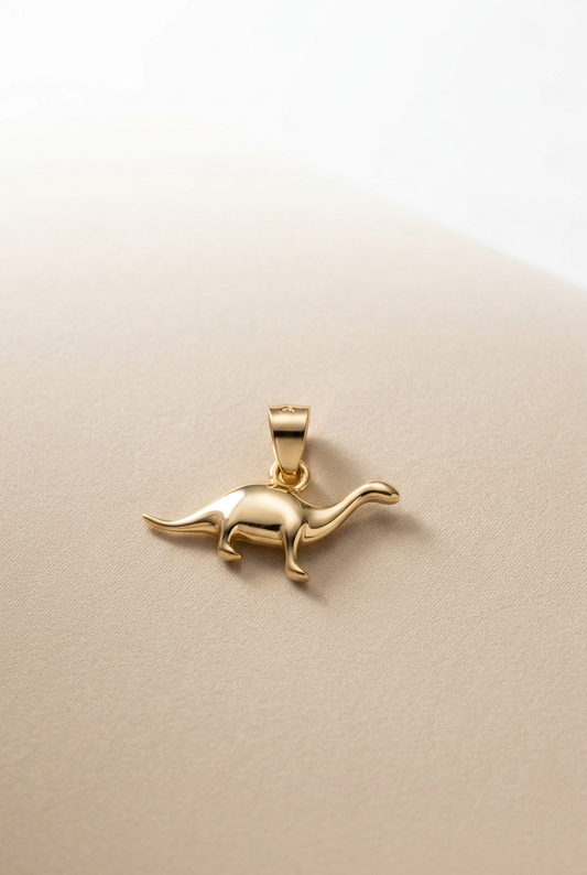 Charm de dinosaurio dorado centrado sobre fondo beige